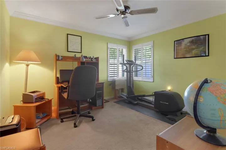 Carpeted office space featuring ornamental molding and a ceiling fan