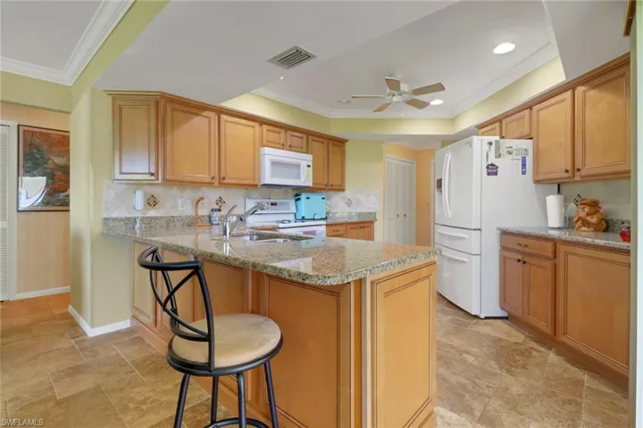 Kitchen featuring a kitchen breakfast bar, ornamental molding, decorative backsplash, a peninsula, and light stone countertops