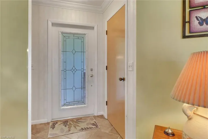 Doorway to outside featuring tile patterned floors and crown molding