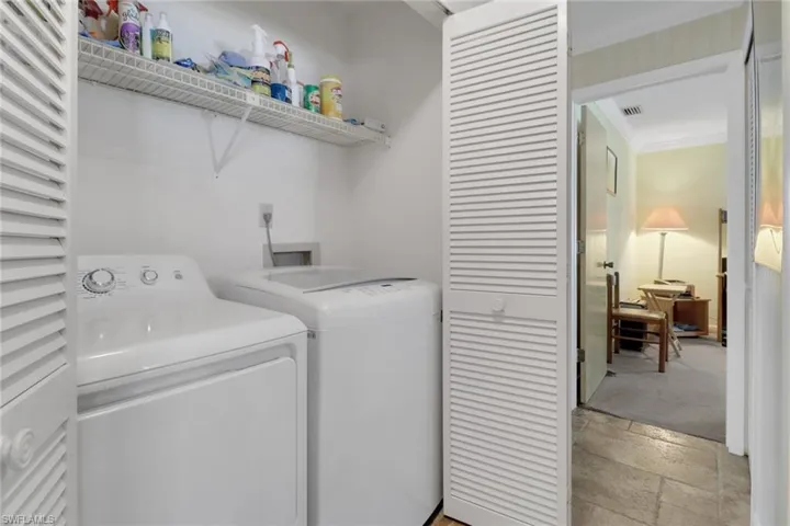 Laundry room with stone tile flooring, ornamental molding, and independent washer and dryer