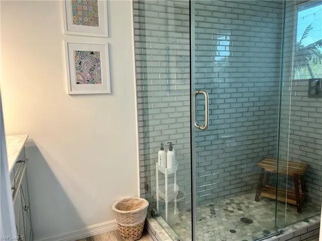 Glass-enclosed shower with subway tile walls and a hexagonal tile floor