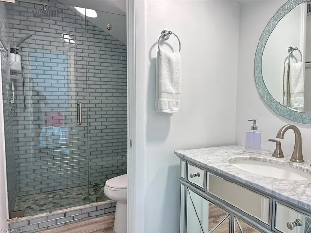 Bathroom featuring a glass-enclosed shower with subway tile, a natural stone shower floor with multiple shower heads