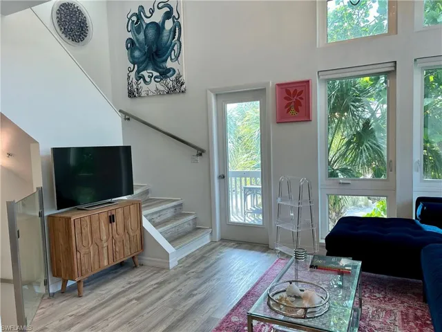 Living area featuring wood-finish flooring and a staircase with a stainless steel handrail