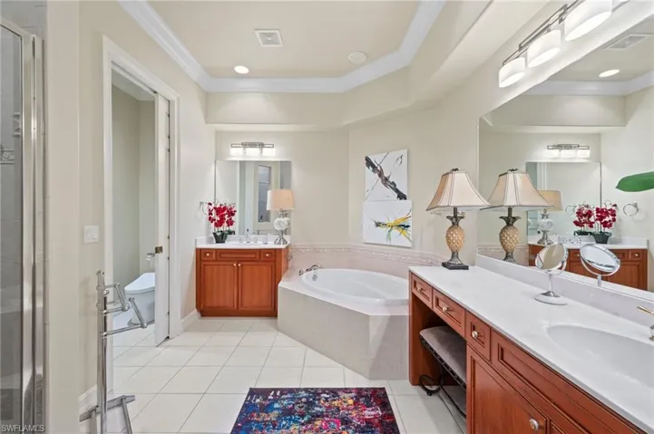 Bathroom featuring a relaxing tub, separate vanities, and toilet