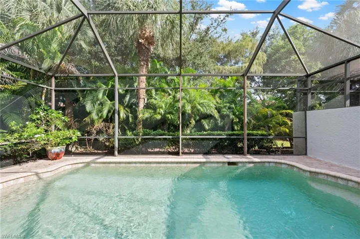 View of pool with screened enclosure and a patio