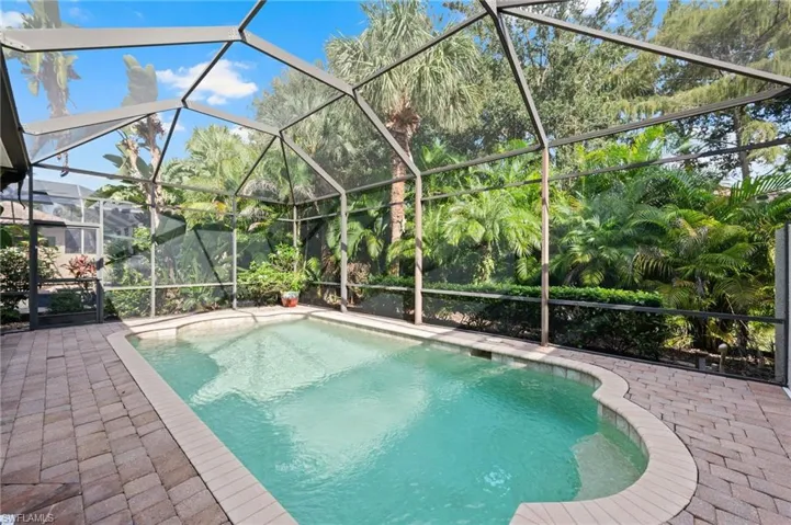 View of pool with screened enclosure and a patio