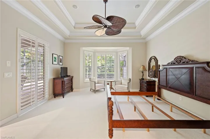 Carpeted bedroom featuring multiple windows, a raised ceiling, and crown molding