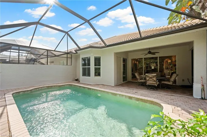 View of pool with screened enclosure and a patio