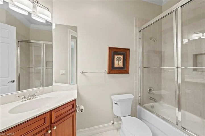 Full bathroom with shower / tub combination with glass door, vanity, toilet, and tile patterned flooring