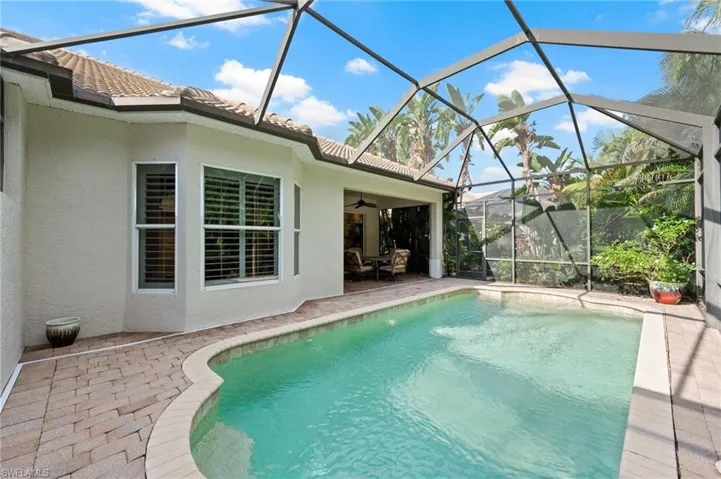 View of pool with screened enclosure and a patio