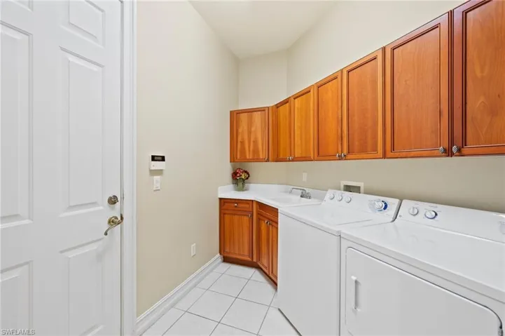 Laundry room featuring cabinets, light tile patterned floors, washer and clothes dryer, and sink