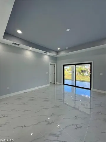 Spare room featuring baseboards, recessed lighting, a tray ceiling, and light marble finish floors