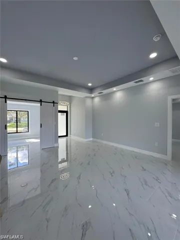 Unfurnished room with a barn door, baseboards, recessed lighting, and marble finish floors