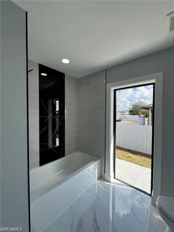 Full bath featuring marble tiled floors, recessed lighting, and tub / shower combination