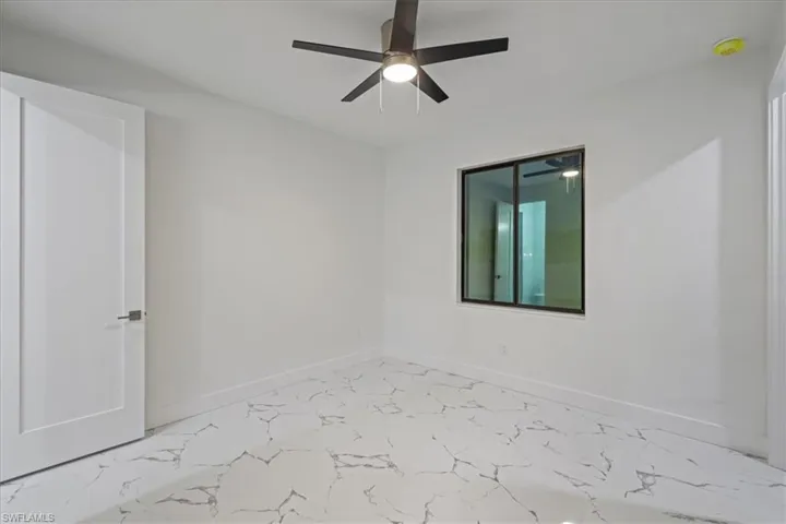 Unfurnished room with marble finish floor, baseboards, and ceiling fan