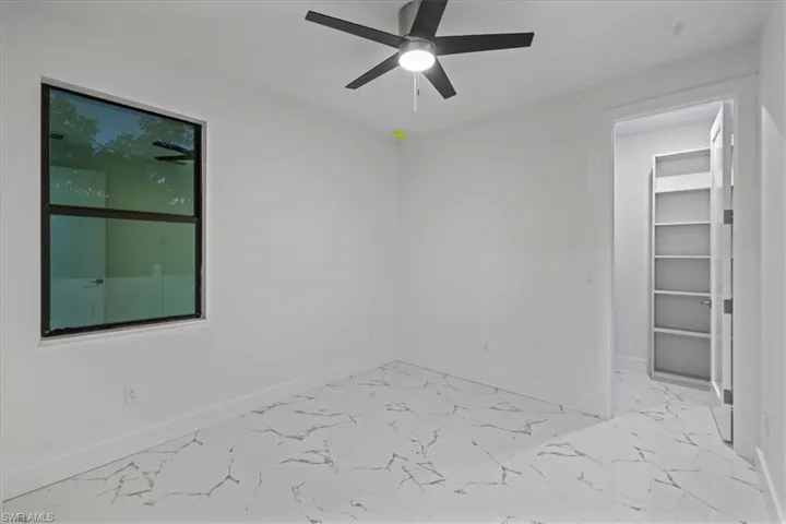 Unfurnished room featuring a ceiling fan, marble finish floor, and baseboards