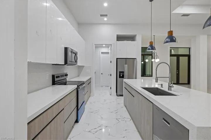 Kitchen featuring modern cabinets, a sink, marble finish floor, and appliances with stainless steel finishes