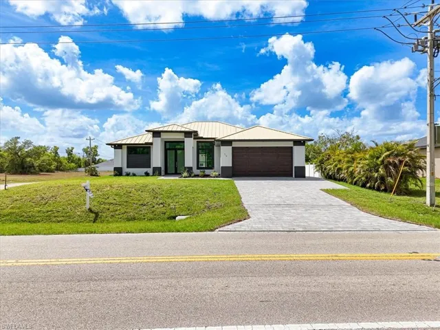 View of front of property featuring metal roof, decorative driveway, a garage, a standing seam roof, and a front lawn