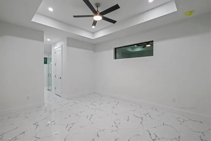 Empty room featuring baseboards, marble finish floor, recessed lighting, a ceiling fan, and a tray ceiling