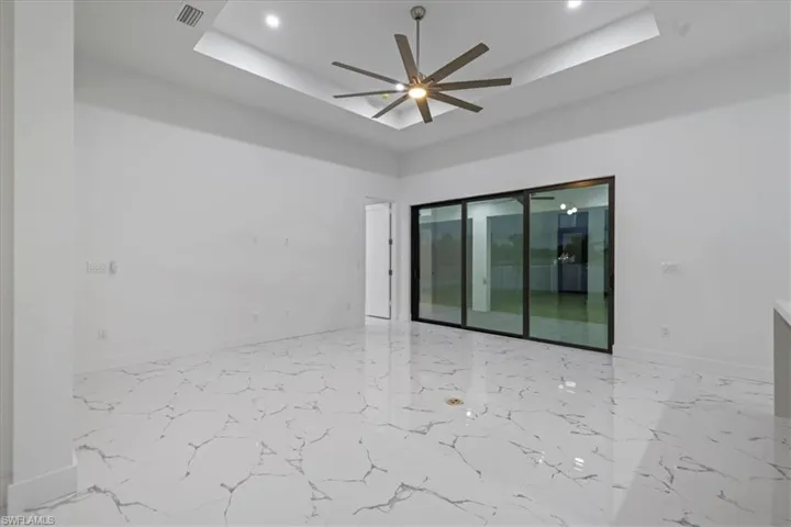 Unfurnished room featuring a tray ceiling, baseboards, marble finish floor, visible vents, and ceiling fan