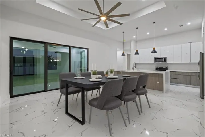 Dining area featuring marble finish floor, a tray ceiling, and ceiling fan