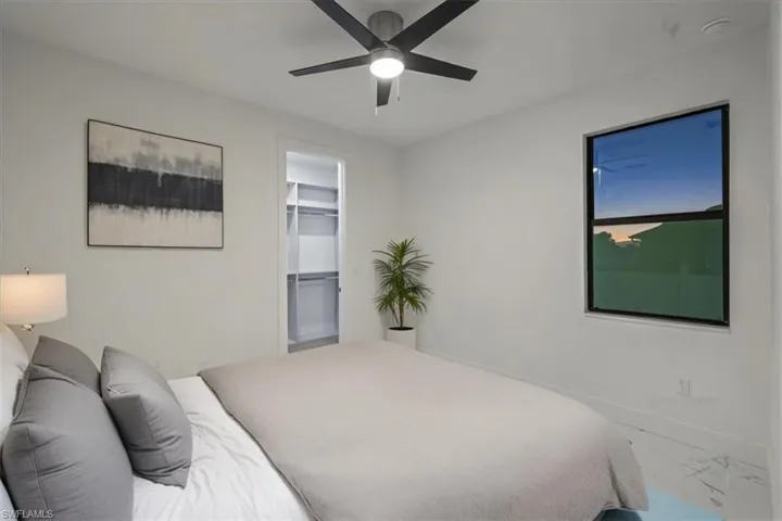 Bedroom with baseboards, marble finish floor, ceiling fan, and a walk in closet