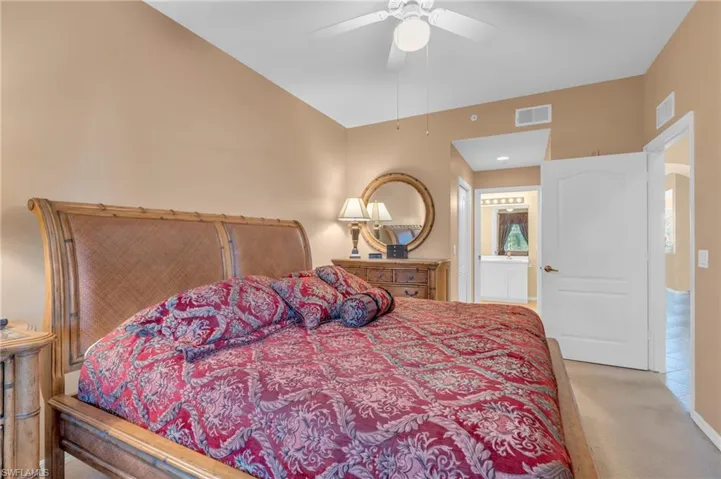 Bedroom with ensuite bathroom, carpet floors, and a ceiling fan
