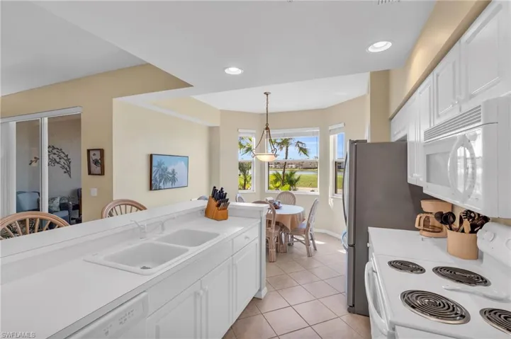 Kitchen with white cabinets, white appliances, light tile patterned flooring, light countertops, and recessed lighting