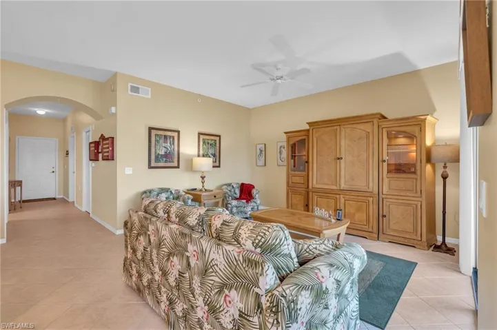 Living area with light tile patterned floors, arched walkways, and ceiling fan