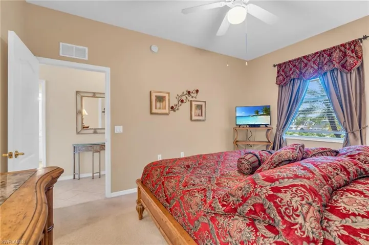 Bedroom featuring light colored carpet, ceiling fan, and light tile patterned floors