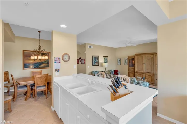 Kitchen featuring light countertops, white cabinetry, light tile patterned flooring, hanging light fixtures, and a ceiling fan