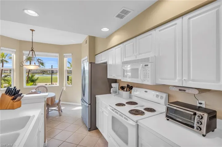 Kitchen with white appliances, white cabinetry, decorative light fixtures, light countertops, and recessed lighting