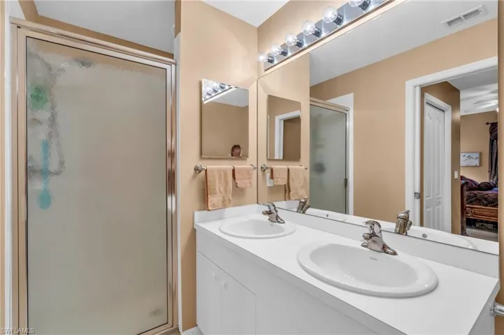Ensuite bathroom featuring a shower stall and double vanity