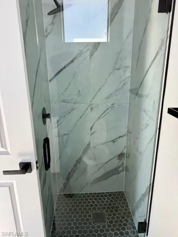STUDIO-Full bath featuring a marble finish shower