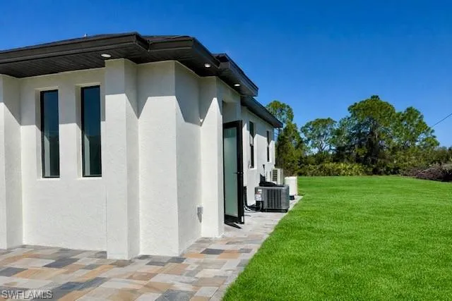 STUDIO WITH PRIVATE ENTRANCE. View of side of property featuring a lawn and stucco siding