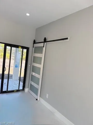 Laundry with a barn door, finished concrete floors, and recessed lighting