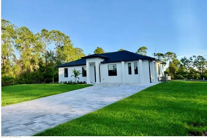 View of front of property with a front yard, stucco siding, and decorative driveway