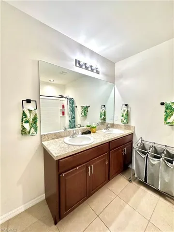 Bathroom with double vanity, a sink, baseboards, and a shower with shower curtain