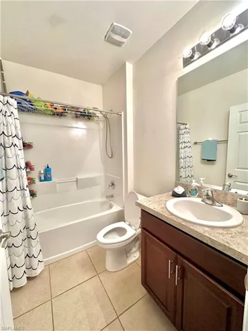 Full bathroom featuring vanity, toilet, tile patterned floors, visible vents, and shower / bath combo