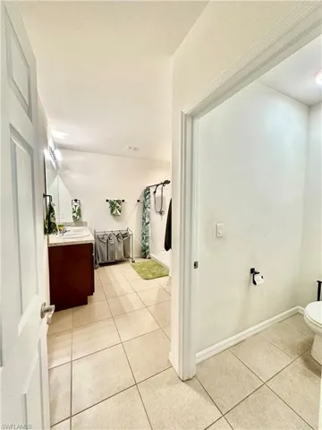 Bathroom with toilet, vanity, curtained shower, tile patterned flooring, and baseboards