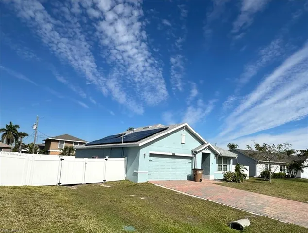 View of front of property featuring a garage, a front lawn, and solar panels