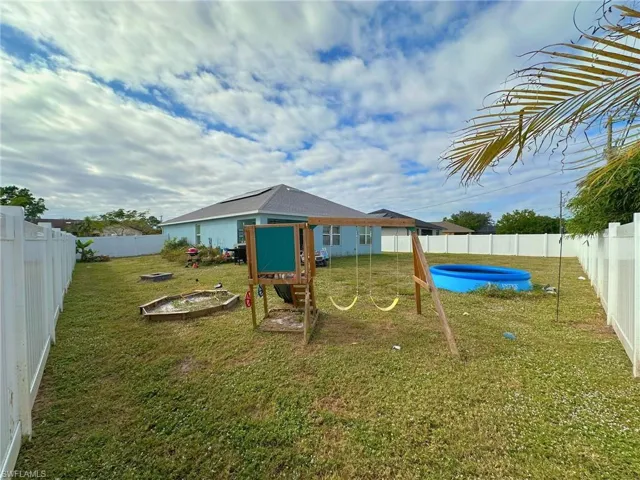 View of jungle gym with a swimming pool and a lawn