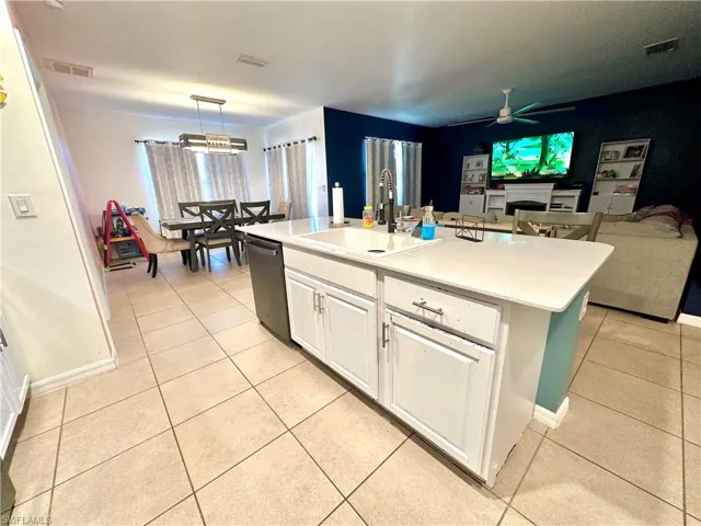 Kitchen with light countertops, visible vents, dishwasher, a ceiling fan, and a sink