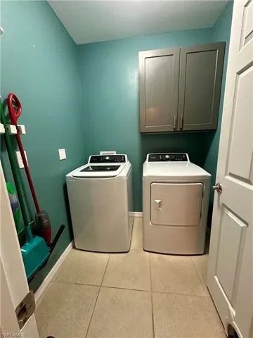 Laundry room featuring baseboards, washer and dryer, cabinet space, and light tile patterned floors