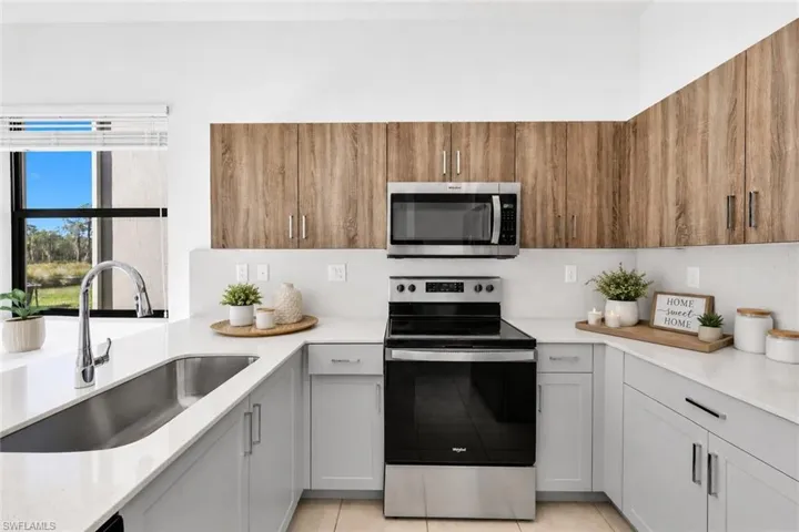 Kitchen with appliances with stainless steel finishes and light stone counters