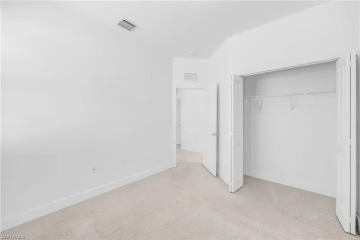 Bedroom featuring light carpet and baseboards