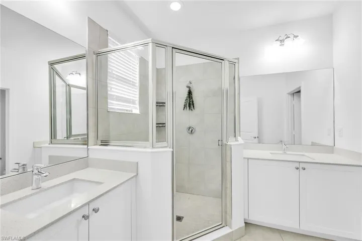 Primary Bathroom with a shower, two vanities, and light tile patterned floors