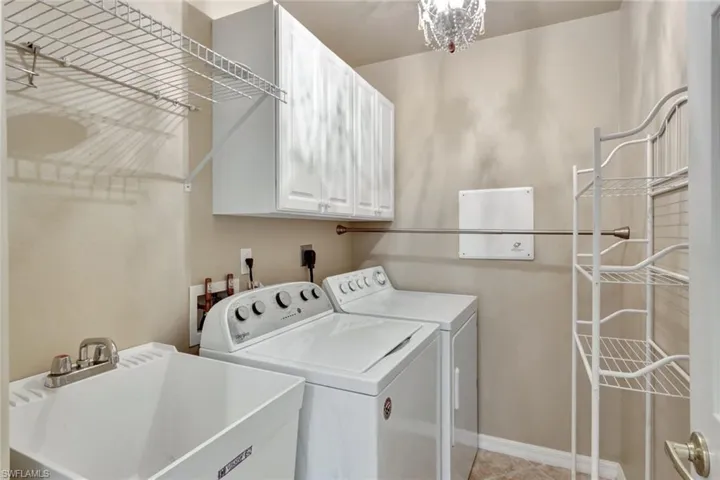 Laundry with tub, cabinetry, clothes rack, & shelving