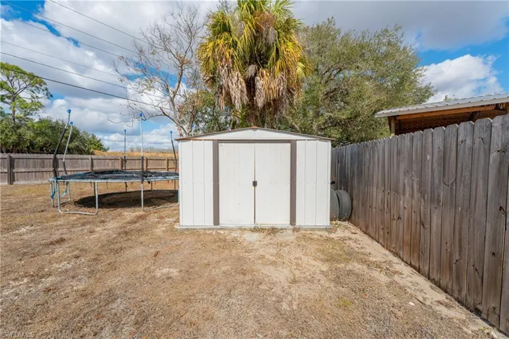 View of shed with a trampoline and a fenced backyard