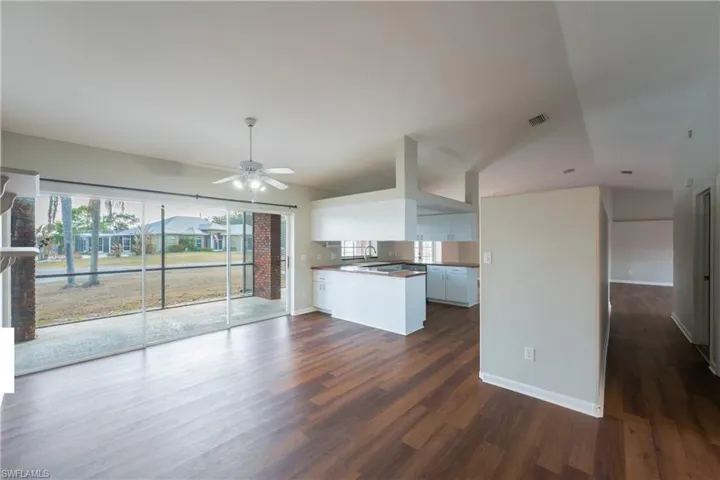 Kitchen featuring a peninsula, vaulted ceiling, white cabinets, dark wood finished floors, and ceiling fan
